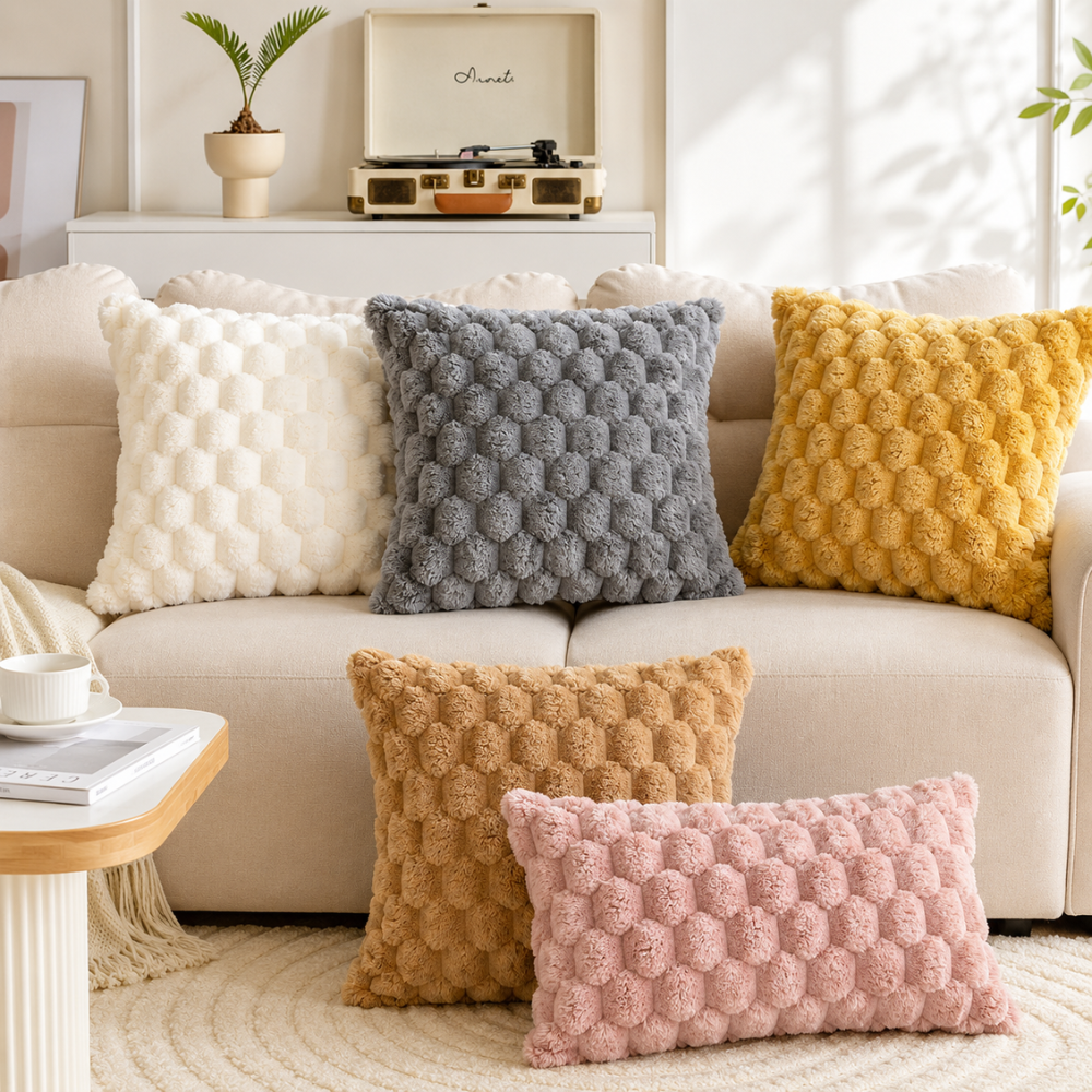Housses de coussin crème, grise, jaune, marron et rose sur un canapé blanc