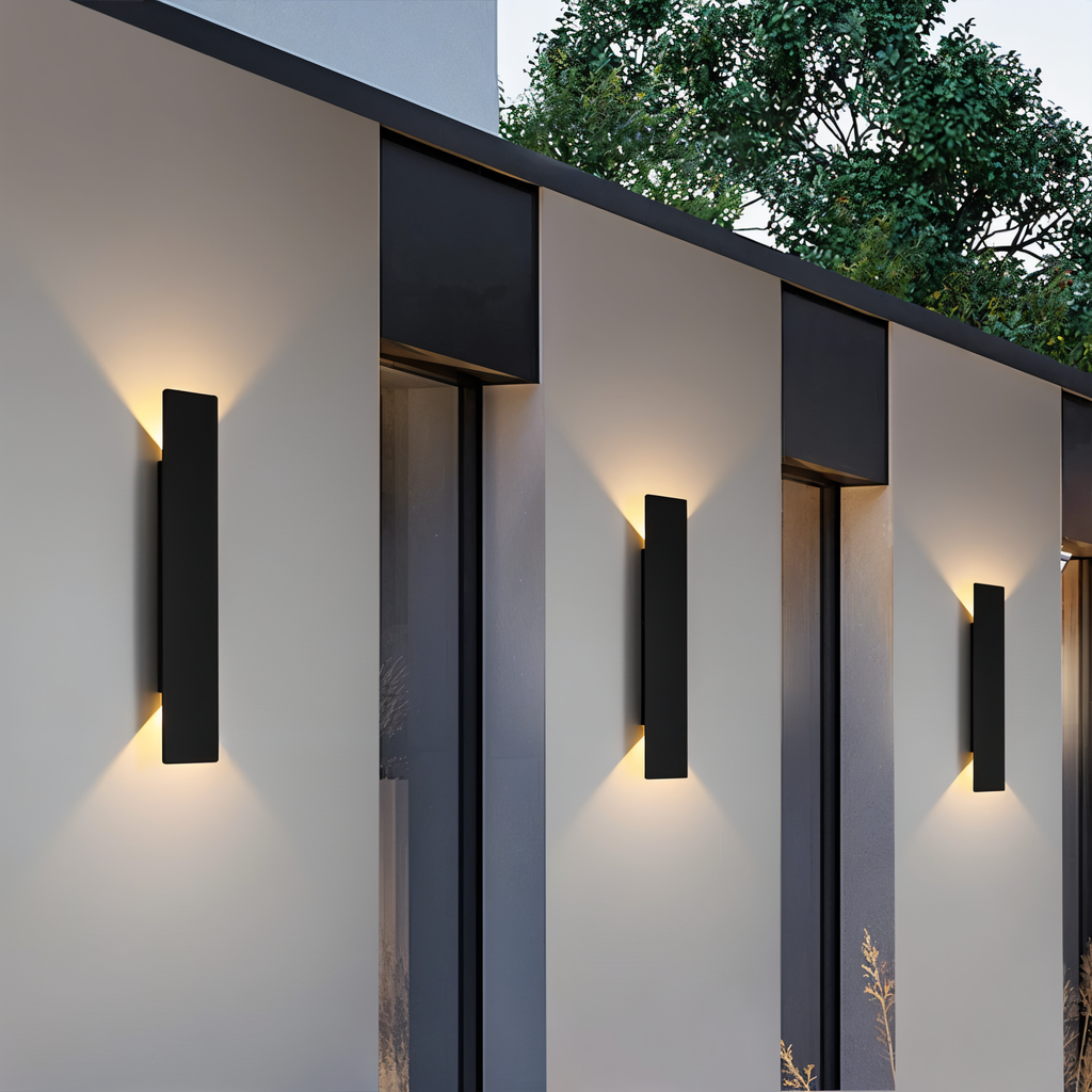 Trois appliques murales noires allumées sur une façade moderne
