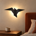 Applique murale oiseau noire à lumière chaude au-dessus de la table de chevet dans la chambre