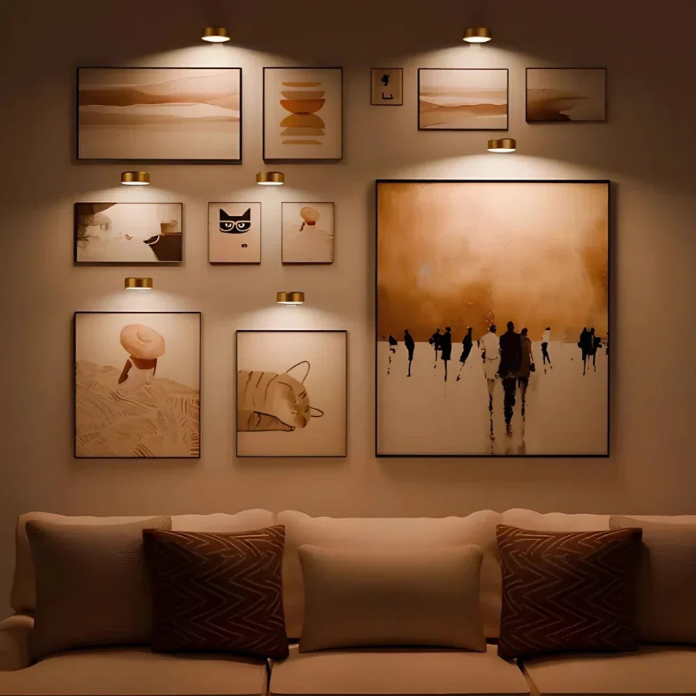 Lampes de tableau dorées au-dessus d'un mur de cadres dans le salon