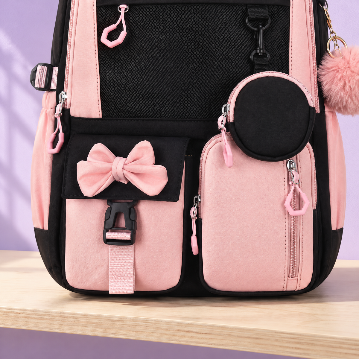 Détail du cartable noir et rose : pochette ronde à nœud, poches avant et boucle