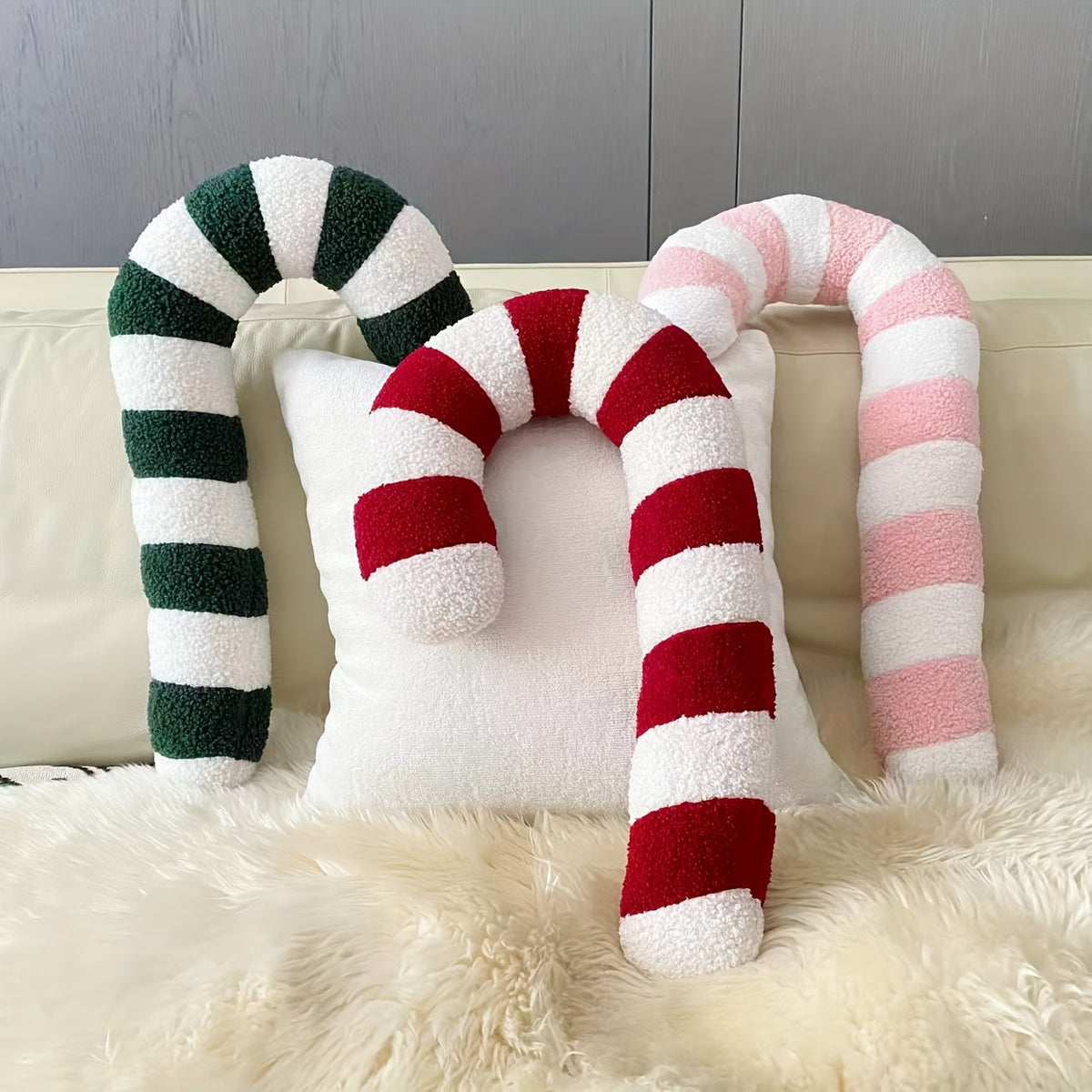 Coussins sucre d'orge vert, rouge et rose sur un canapé avec un tapis en fourrure