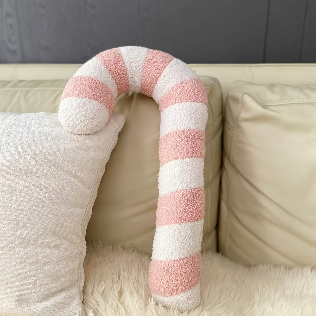 Coussin sucre d'orge rose sur un canapé avec un plaid en fourrure