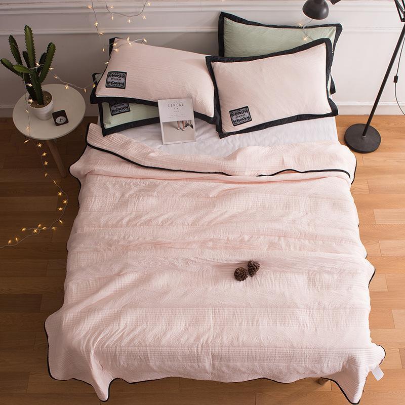 Couverture rafraîchissante rose sur un lit avec coussins assortis