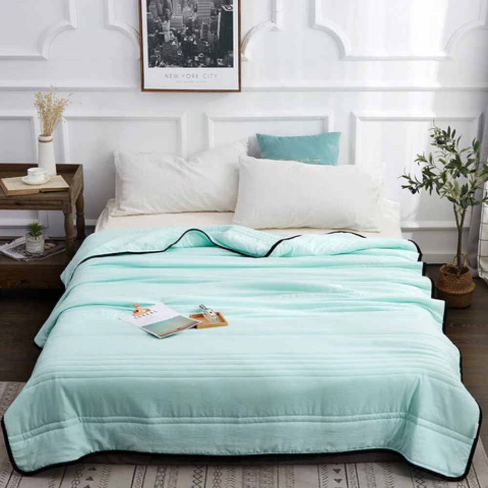 Couverture rafraîchissante vert menthe étalée sur un lit blanc