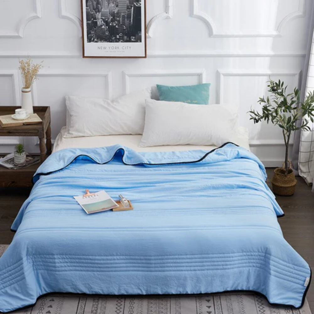 Couverture rafraîchissante bleue étalée sur un lit blanc