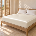 Drap-housse aspect satiné blanc sur un lit double dans une chambre méditerranéenne aux volets mi-clos