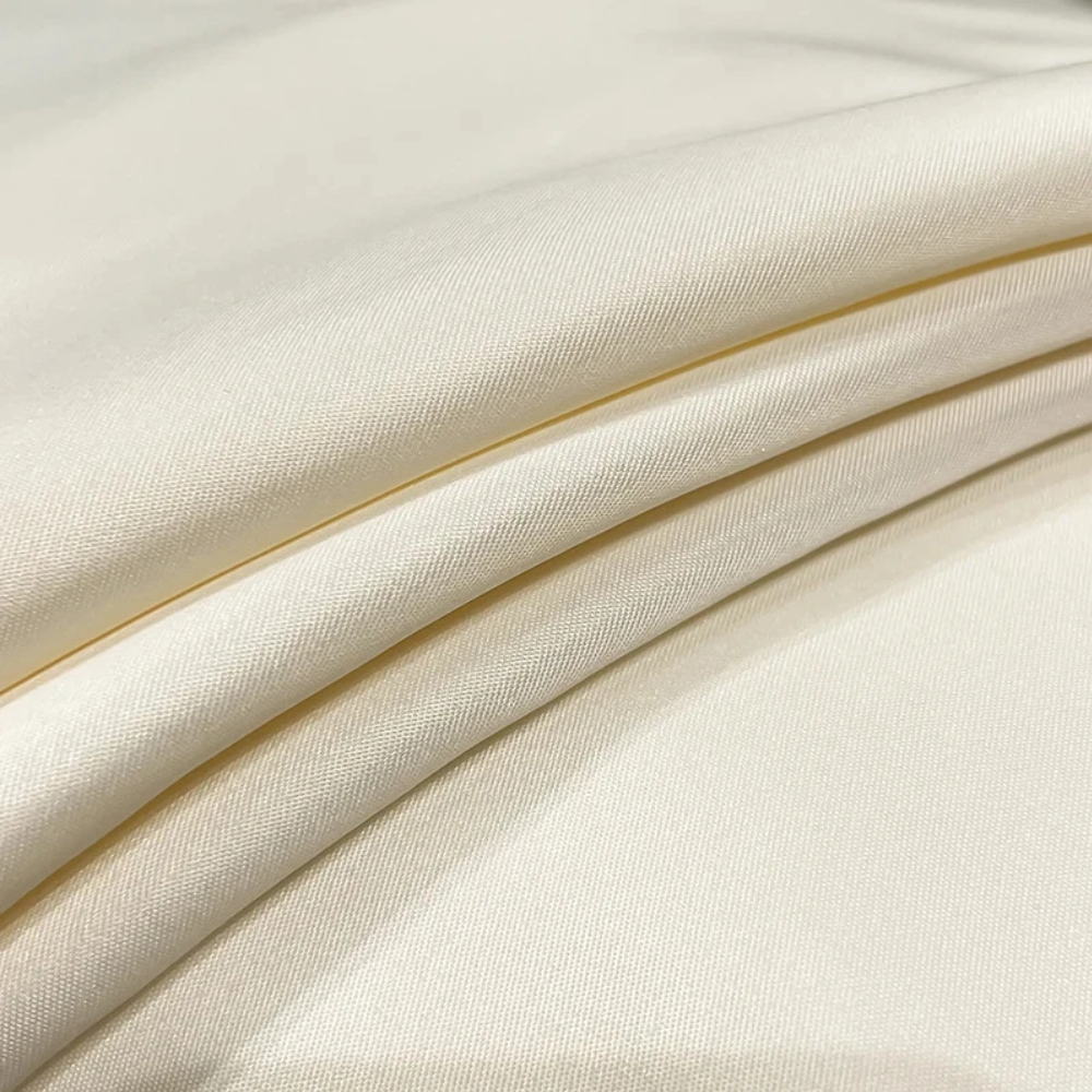 Gros plan sur le tissu lisse du drap-housse aspect satiné crème