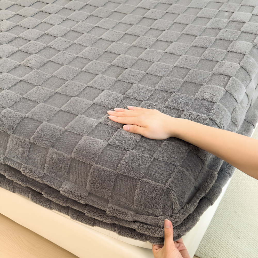 Main qui caresse le tissu moelleux à carreaux du drap-housse gris