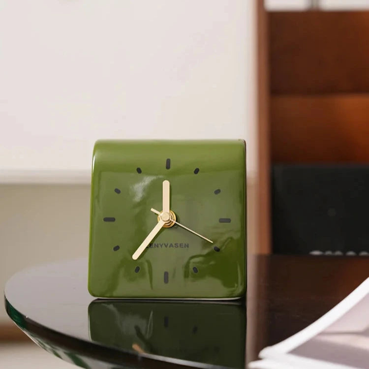 Horloge à poser vert olive sur une table en verre
