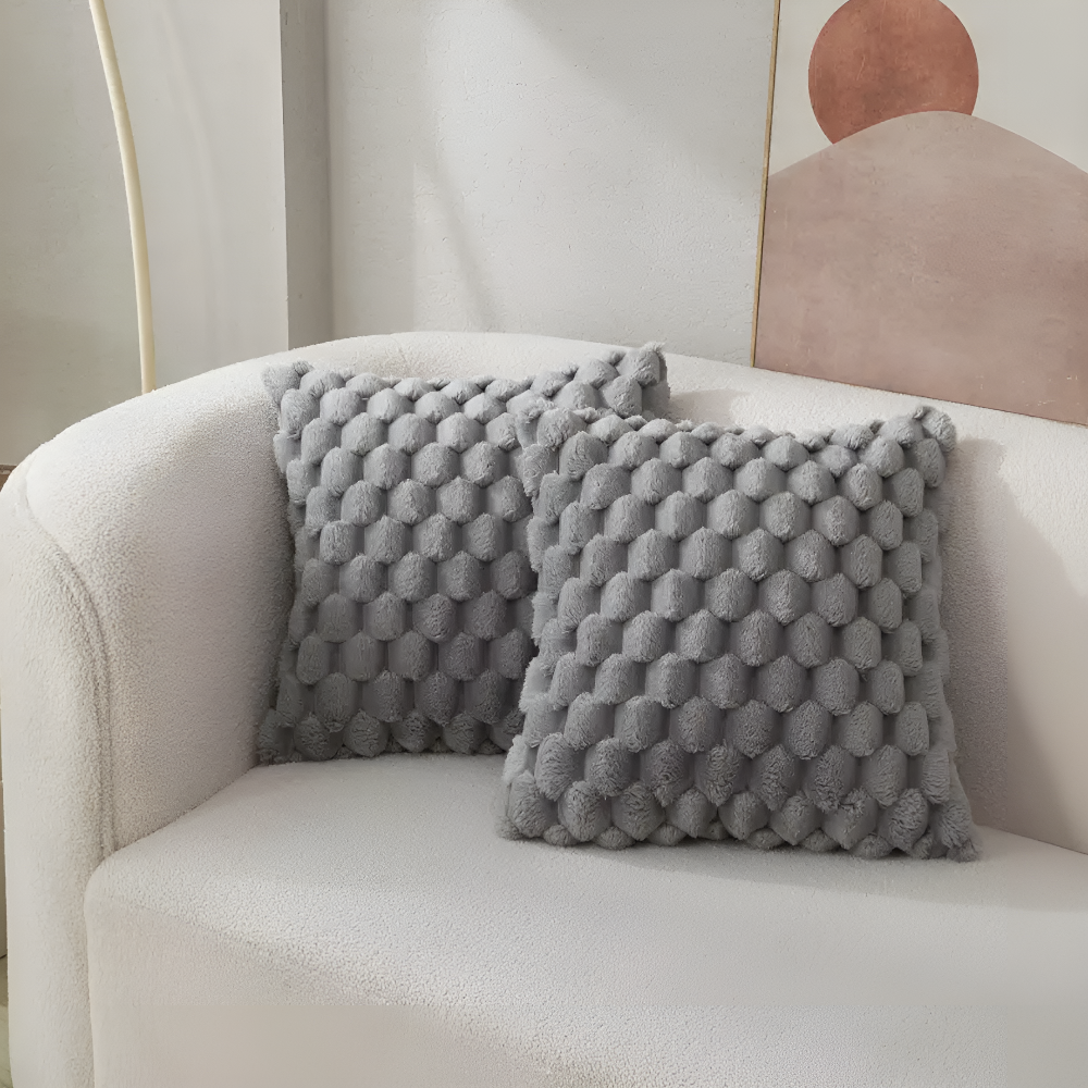 Housses de coussin grises à relief bulles sur un canapé blanc