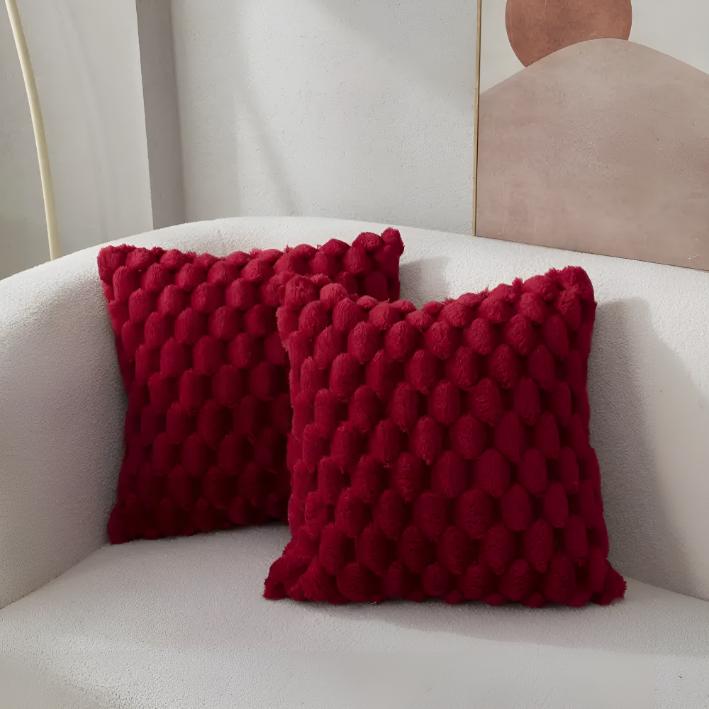 Housses de coussin bordeaux à relief bulles sur un canapé blanc