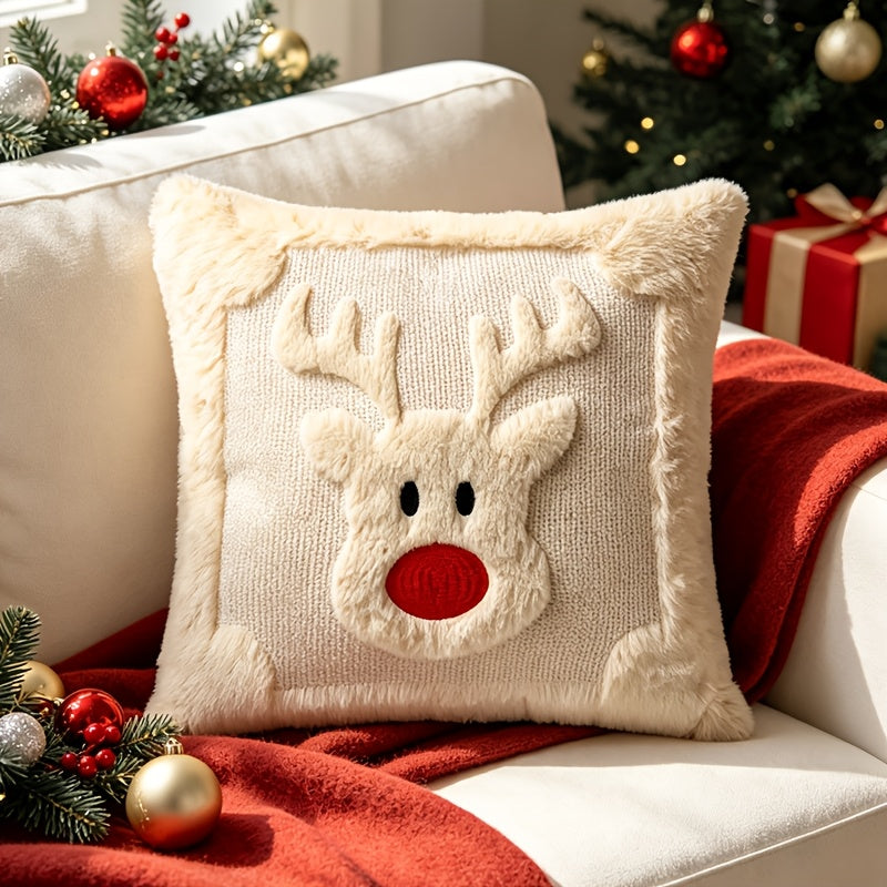 Housse de coussin crème avec renne au nez rouge sur un canapé avec un plaid rouge
