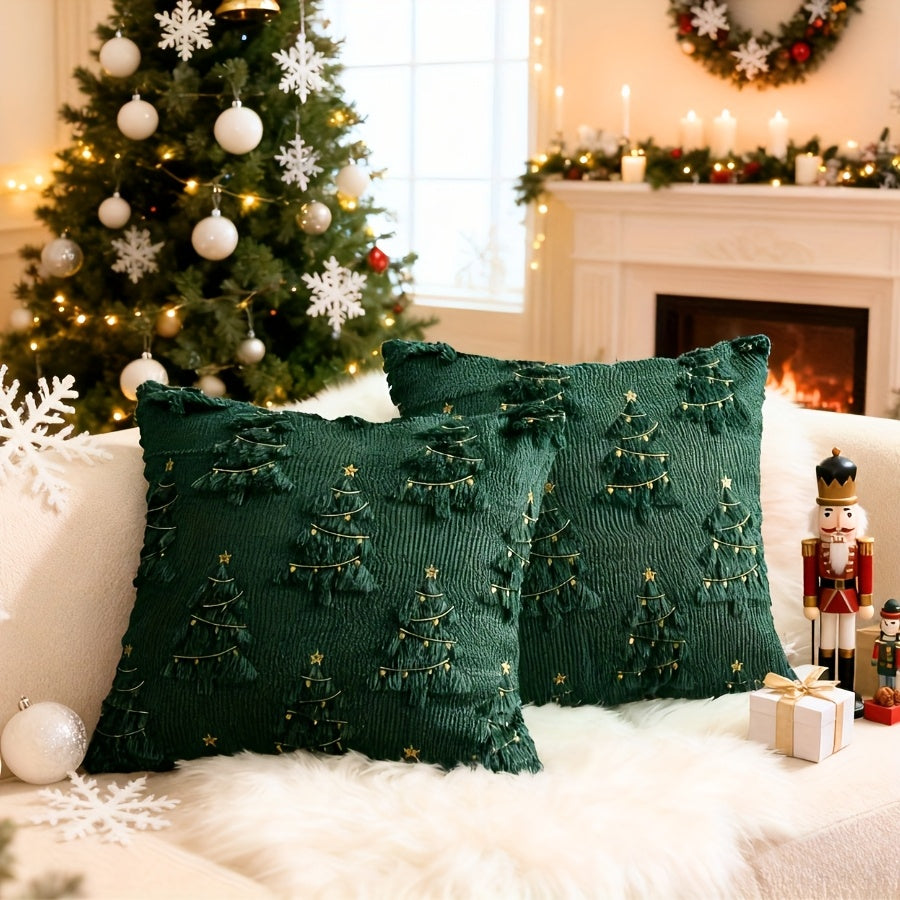Deux housses de coussin de Noël vertes à sapins en relief et étoiles sur un canapé blanc devant le sapin de Noël