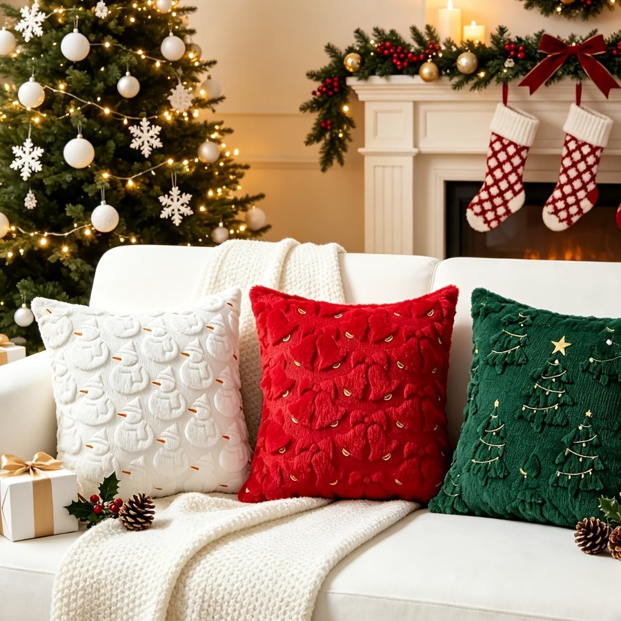 Housse rouge à cloches et housse verte à sapins sur un canapé blanc, à côté d'un coussin blanc de décoration non vendu