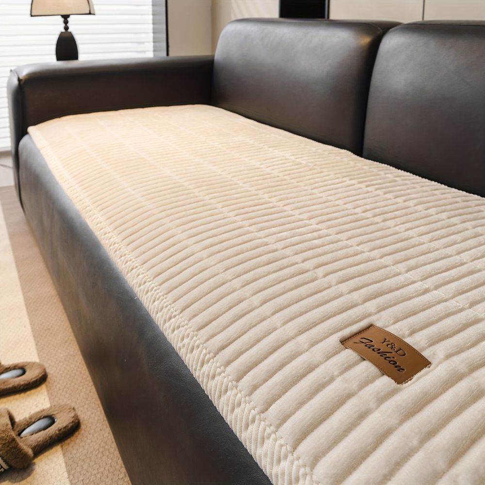 Jeté de canapé matelassé crème sur un canapé en cuir noir