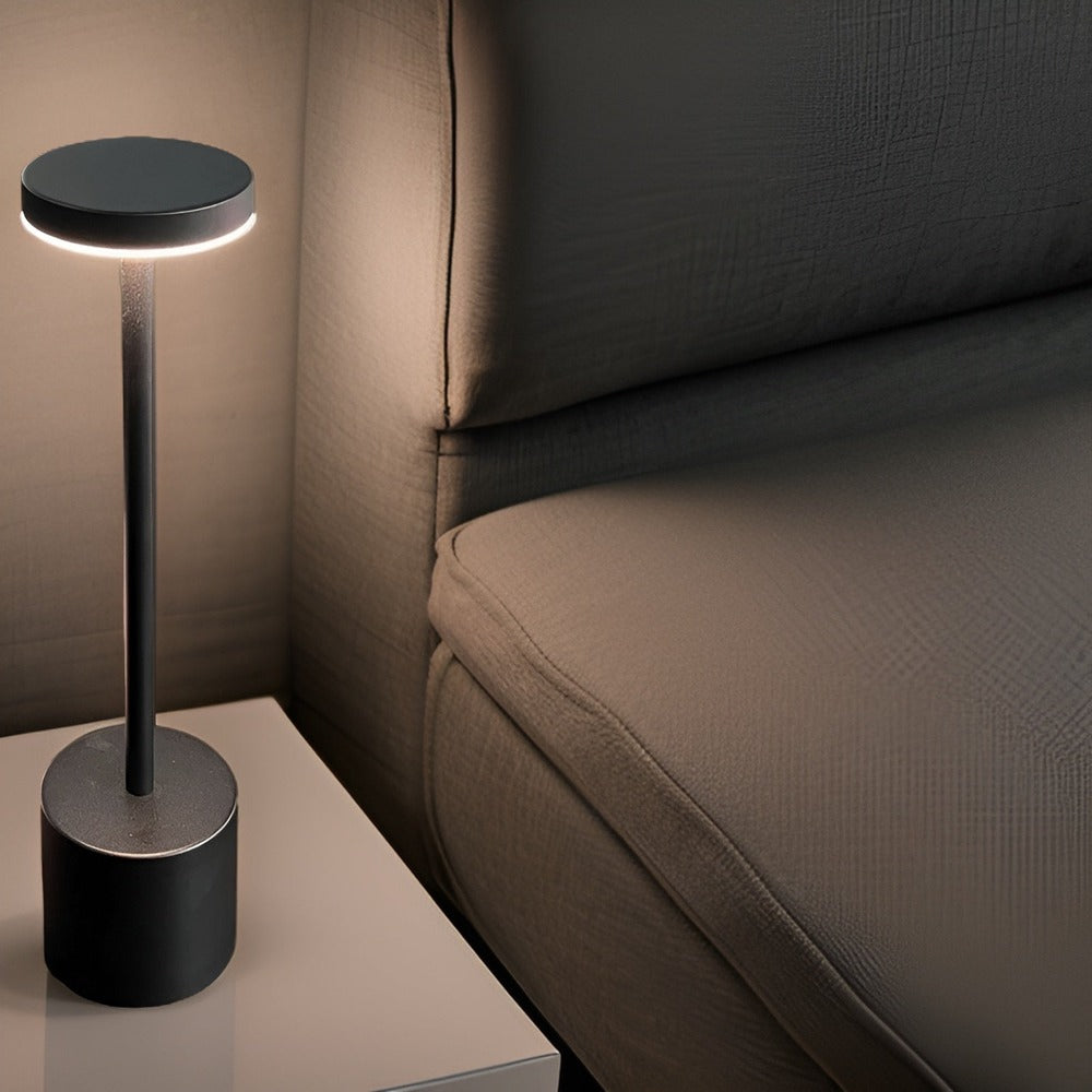 Lampe de table sans fil noire allumée près d'un canapé
