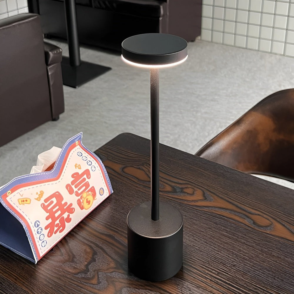 Lampe de table sans fil noire allumée sur une table en bois