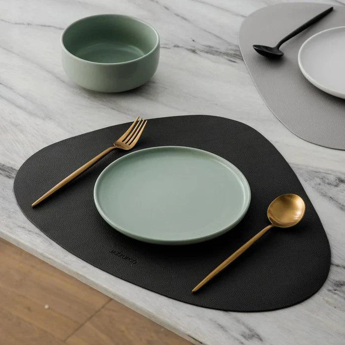 Couverts dorés sur un set de table noir avec vaisselle vert d'eau