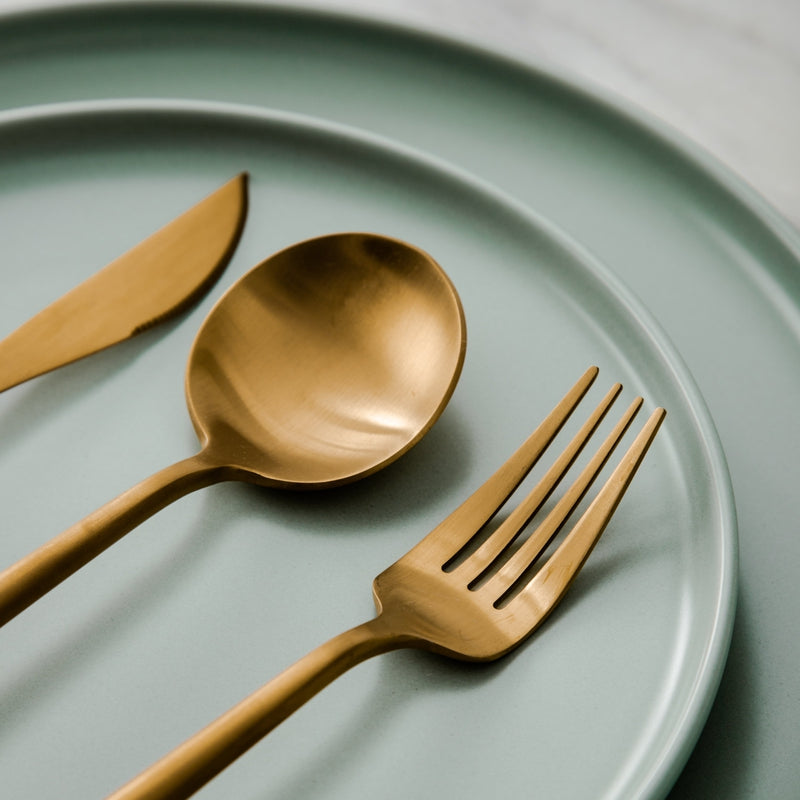 Cuillère et fourchette dorées sur une assiette verte