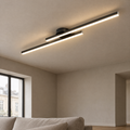 Plafonnier LED linéaire noir allumé au plafond d'un salon aux murs à la chaux
